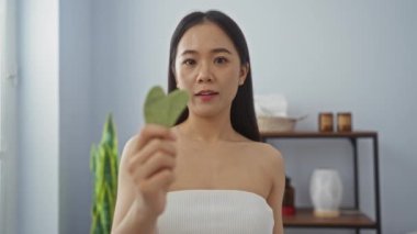 Çin 'deki sağlık merkezinde kalp şeklinde yaprak tutan bir kadın güzellik ve rahatlama gösteriyor.