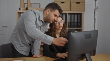 Kadın ve erkek, ofis içi bir bilgisayarın başında birlikte çalışıyorlar. Takım çalışması üzerine yoğunlaşmış bir iş ortamı öneriyorlar.
