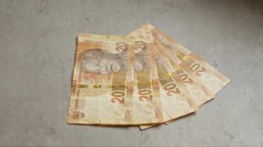 Güney Afrikalı yirmi rand banknotları beton bir yüzeye yayılmış, Mandela 'nın portresini ve karmaşık tasarımlarını vurguluyor.