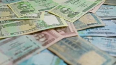 Bangladeş banknotları, düz bir yüzeye dağılmış, çeşitli mezhepleri ve bangladeş para biriminin karmaşık tasarımlarını vurgulayan, ulusal figürleri ve mimariyi betimleyen banknotlar.