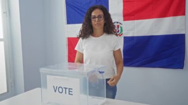 Dominik Cumhuriyeti bayrağının önünde elinde oy sandığıyla duran kadın, vatandaşlık bağını ve demokratik süreci vurguladı.