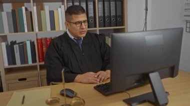 Yargıç cüppeli İspanyol adam arka planda kitap ve dosyalarla bir ofiste video konferansı düzenliyor..