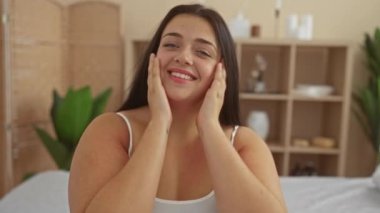 Kadın spa salonunda dinlenmekten zevk alıyor, gülümsüyor ve huzur dolu bir sağlık odasında poz veriyor.