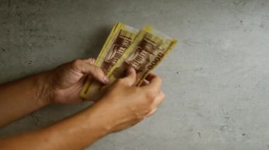 Elleri Macar forint banknotlarını somut bir arka plana karşı sayarak, insanların para tutarken kullandıkları finansal temayı vurguluyor.