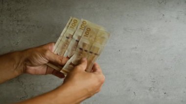 Adam elleri beton zeminde Danimarka kronu banknotları sayıyor.