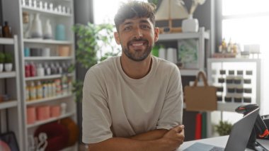 Dekoratif eşyalarla dolu bir mağazada gülümseyen genç adam.