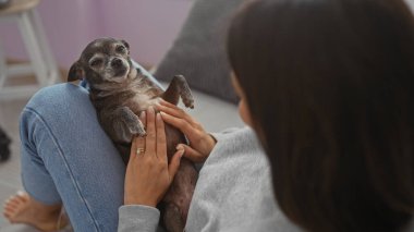 Genç bir İspanyol kadın evde köpeğiyle sarılıp, ev ortamında evcil hayvanıyla bağ kuruyor..