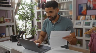 Çekici dekorasyonlarla çevrili iyi düzenlenmiş bir ev dekorasyonu mağazasında evrak işlerini yöneten genç bir adam, kapalı alanda verimli iş uygulamaları gösteriyor..