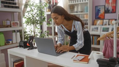 Dizüstü bilgisayarda çalışan genç bir kadın güzel dekore edilmiş bir mağazada çeşitli dekorasyon ürünleri sergiliyor.
