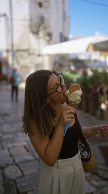 Genç bir İspanyol kadın, Puglia, İtalya 'nın eski caddelerinde dondurma yiyip Avrupa' da güzel bir anı yakalıyor..