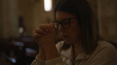 Genç, güzel bir İspanyol kadın gözlerini kapatıp dua ediyor ve İtalya 'da tarihi bir kilisenin içinde, kasvetli ve dindar bir Hıristiyan atmosferini yakalıyor..