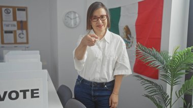 Orta yaşlı İspanyol kadın, Meksika 'da bir seçim odasını işaret ediyor. Elinde bayrak ve 