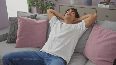 İspanyol adam modern mobilyalı bir dairede rahatça dinleniyor.