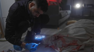 İspanyol dedektif olay yerini büyüteçle, kanla ve çarşafın altında cesetle inceliyor.