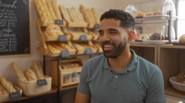Ekmek ve hamur işleriyle dolu bir fırında gülümseyen yakışıklı bir adam, sıcak ve davetkar bir atmosfer sergiliyor.