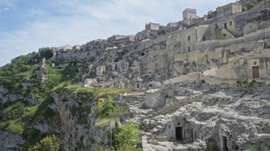 Tarihi şehir Materia, Basilicata, İtalya 'da mavi gökyüzünün altındaki engebeli bir yamaçtaki antik taş binalar ve evler.