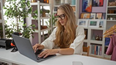 Güzel dekore edilmiş bir ev dekorasyonunda dizüstü bilgisayarda çalışan genç bir kadın.