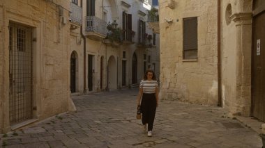 Genç bir İspanyol kadın tarihi Lecce, Puglia, İtalya 'da eski taş binalar ve dar sokaklar tarafından çevrelenmiş büyüleyici bir kaldırım taşı caddesinde yürüyor..