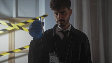 Yakışıklı İspanyol dedektif, kapalı mekan suç mahallindeki kanıtları odaklanmış ifadeyle analiz ediyor..
