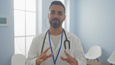 Yakışıklı İspanyol erkek doktor. Parlak bir klinikte konuşuyor.