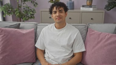 Yakışıklı, genç, İspanyol bir adam modern bir salonda öylesine oturuyor..