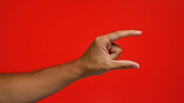 Parlak kırmızı arka planda küçük boy el hareketi yapan adam..