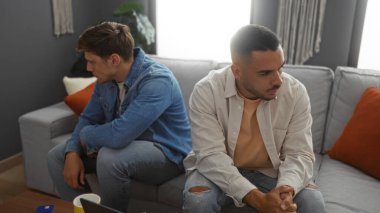 Erkek arkadaşlar bir apartman dairesinde oturmuş birbirlerine bakmıyorlar.