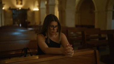 Genç bir İspanyol kadın, ahşap bankların ve dini mimarinin huzurlu atmosferiyle çevrili İtalya 'da bir Hıristiyan kilisesinde dua ediyor..