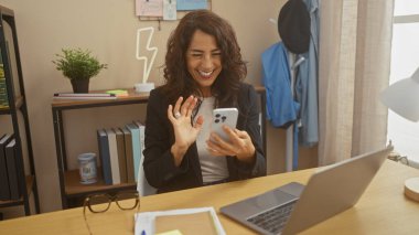 Samimi bir ofis ortamında akıllı telefonundan gülümseyen bir kadın videosu..