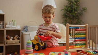 Toddler boy playing with colorful toys in a cozy indoor kindergarten with wooden shelves in the background and natural light illuminating the scene clipart