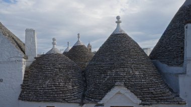 Trulli evleri Alberobello 'da, İtalya' nın Puglia, Avrupa 'da bulutlu bir gökyüzünün altında gri taştan yapılmış ikonik çatılar..