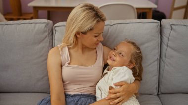 Kafkas anne ve kızı rahat oturma odalarında rahat bir kanepede birlikte sevgi dolu bir anı paylaşıyorlar..