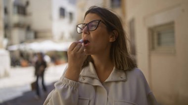 Latin kökenli genç bir kadın, tarihi Avrupa mimarisinin bulanık geçmişine sahip eski şehir barisi, puglia, İtalya sokaklarına dudak kremi sürüyor..