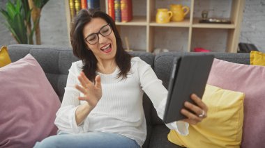 Keyifli bir kadın videosu, sıcak oturma odasından ekranına el sallayarak tablete sesleniyor..