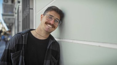 Şehir sokaklarında gülümseyen, şehir ortamında neşeli bir hava taşıyan, bıyıklı yakışıklı İspanyol bir adam..