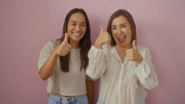 Anne ve kızı pembe bir arka plana karşı mutlu yüz ifadeleriyle başparmaklarını göstererek aile sevgisini ve birlikteliğini resmediyorlar.