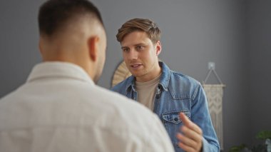 Erkekler sıcak bir oturma odasında konuşuyorlar, içerde rahat bir atmosferi olan arkadaşlar arasında bir an konuşuyorlar.