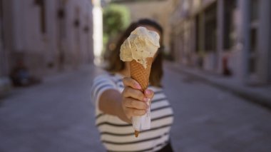 Genç İspanyol bir kadın elinde dondurma külahıyla Lecce, Puglia, İtalya 'da büyüleyici bir şehir sokağının bulanık geçmişiyle.