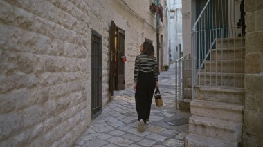 Genç, güzel, İspanyol bir kadın polignano 'nun büyüleyici taş sokaklarında yürüyor. Bir kısrak, puglia, İtalya, elinde sepeti tutuyordu..