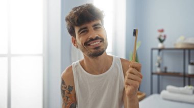 Kapalı kaplıcada diş fırçası tutarken gülümseyen sakallı yakışıklı bir İspanyol.