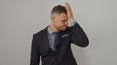 Takım elbiseli genç bir adam beyaz bir arkaplan karşısında stresli görünüyor, evrensel bir endişe veya hata ifadesi sergiliyor..