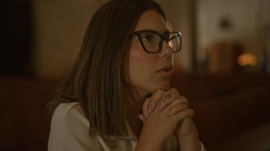 Gözlüklü genç bir İspanyol kadın İtalya 'da bir kilisede oturmuş, dua ediyor, dingin bir Hıristiyan ayinini vurguluyor..