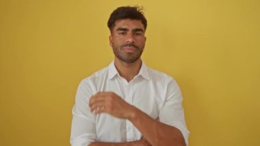 Düşünceli duruşu olan yakışıklı genç adam sarı arka planda izole edilmiş beyaz gömlekli.