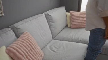 Genç adam rahat bir kanepede rahat bir oturma odasında pembe yastıklarla dinleniyor.
