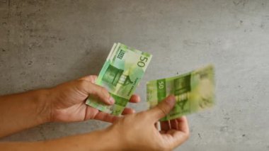 Norveç 'te finans ve para yönetimi vurgulanarak, somut bir arka plana karşı Norveçli kron banknotlarını tutan erkek eller
