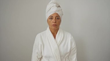 Kafasında bornoz ve havlu olan kadın deli gibi görünüyor ve elleri başının üstünde, ağzı açık korkmuş, şok olmuş ve şaşırmış bir halde, soyutlanmış beyaz bir geçmişi var, orta yaşlı bir kadın.