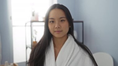 Kaplıca odasında beyaz bornoz giyen, genç ve çekici, uzun siyah saçlı, kameraya öpücük yollayan, rahatlatıcı ve güzel bir kadın..