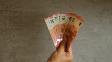Somut bir arkaplan karşısında birkaç avroluk banknot tutuyor