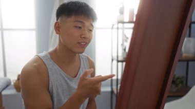 Bir kaplıca odasında aynayla konuşan, kolsuz tişört giyen ve odaklanmış görünen genç bir adam, huzur ortamında içgözlem unsuru ekler..