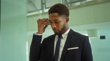 Takım elbiseli genç adam ofiste dikilip dikkatle dinliyor ve akıllı telefonuyla sesli mesaj yolluyor.